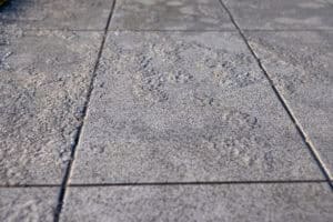Close-up view of several textured concrete pavement tiles with visible seams and uneven surface patterns, highlighting the importance of paver protection during harsh freeze-thaw cycles.